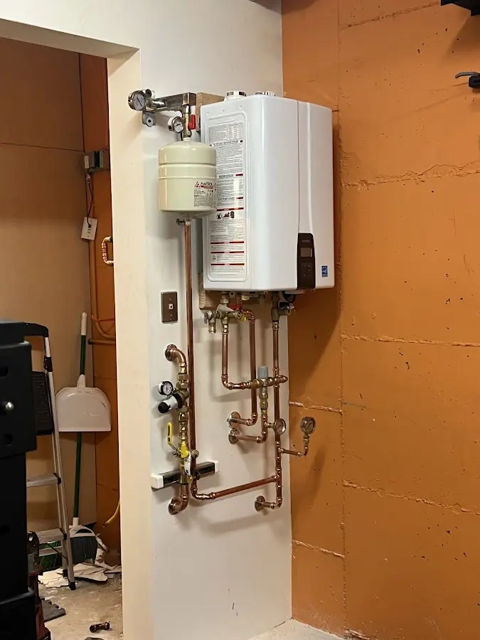 Plumbing technician inspecting water heater connections in Monroe